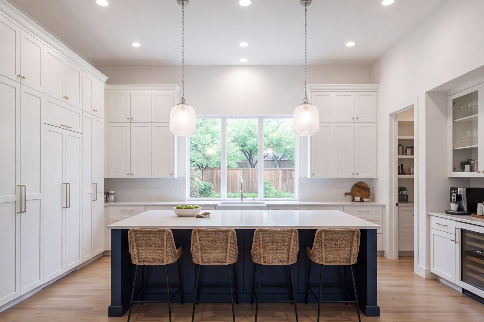 Wide shot of a remodeled kitchen with full-height cabinets, an island and bright overhead lighting